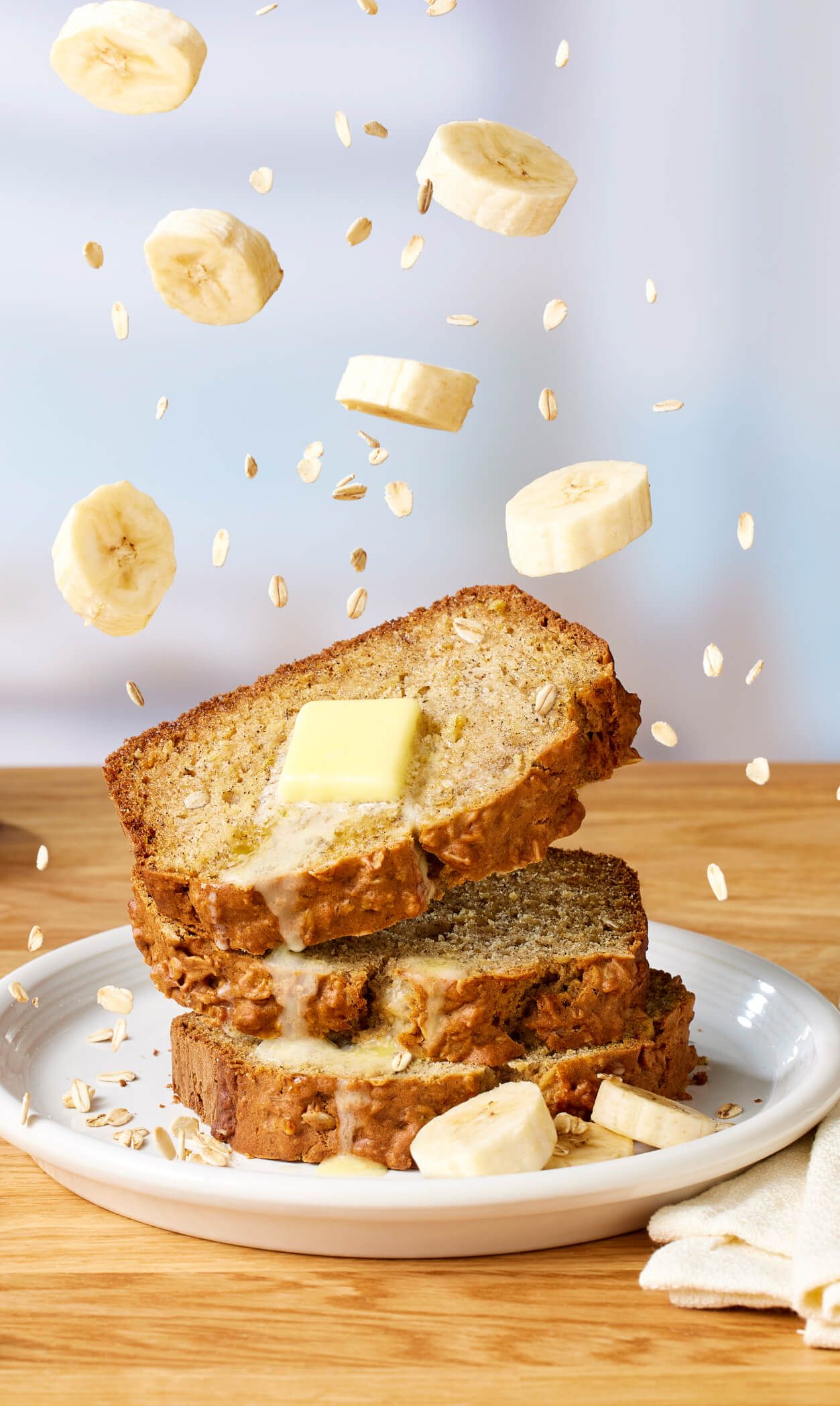 Sliced banana bread with butter, bananas, and oats.